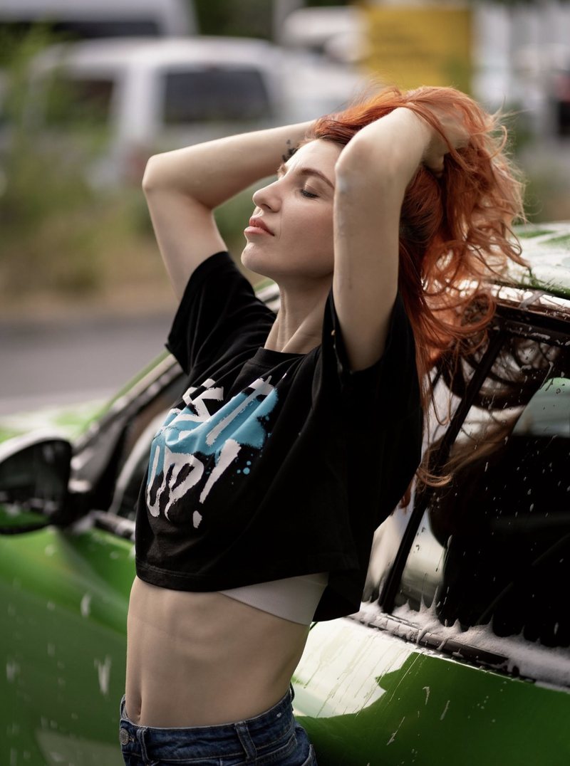 Dariia im schwarzen T-Shirt an einem grünen Auto