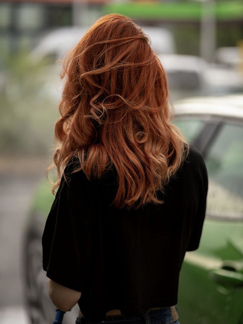 Dariia von hinten mit roten Haaren an einem grünen Auto